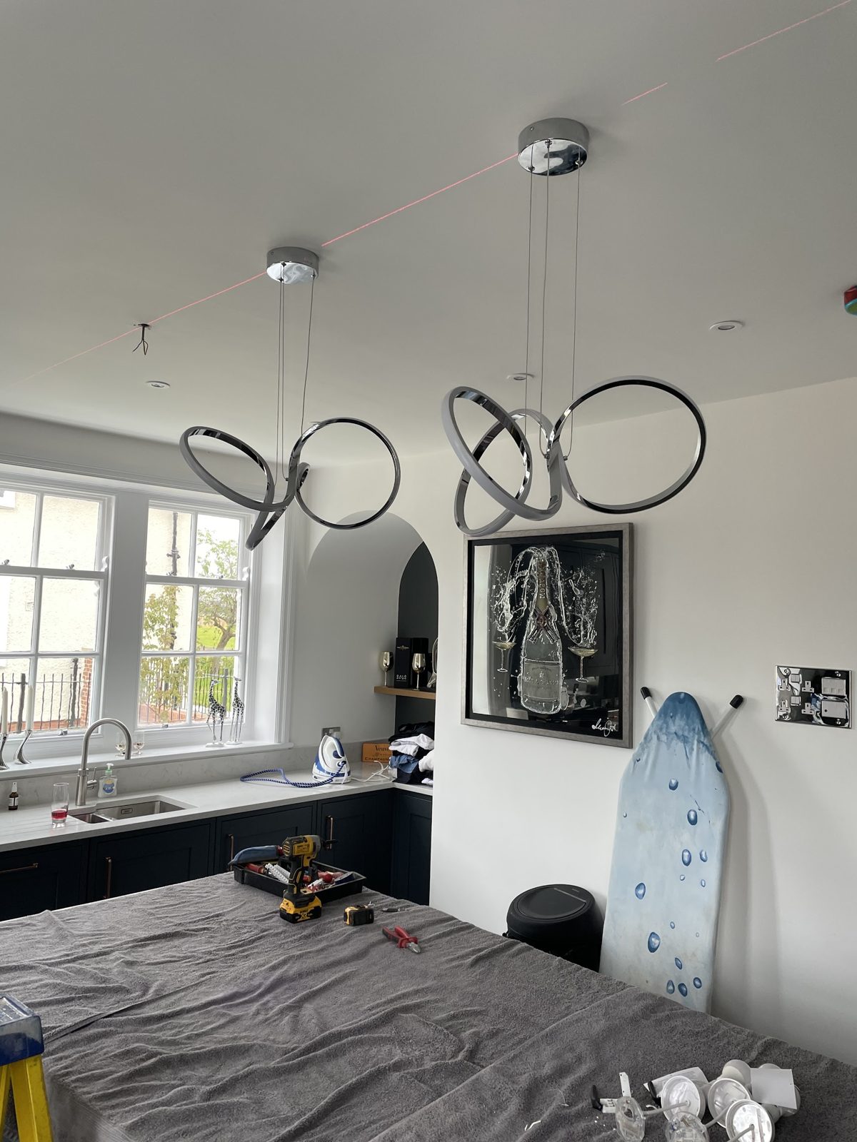 Twisted ring pendant lights hung over a kitchen island, with the worktop covered by a dust sheet