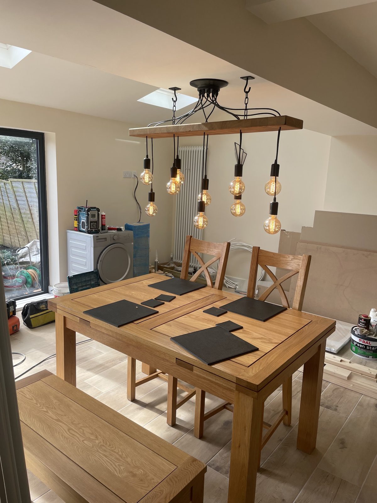 A dining room with a timber bar pendant holding six filament bulbs over an oak table